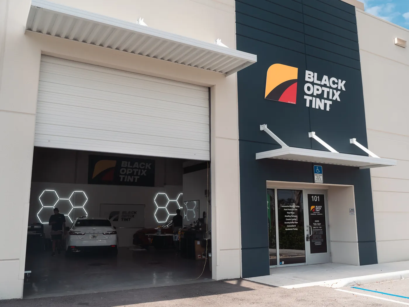 Black Optix Tint storefront with the bay door open and a car being tinted inside