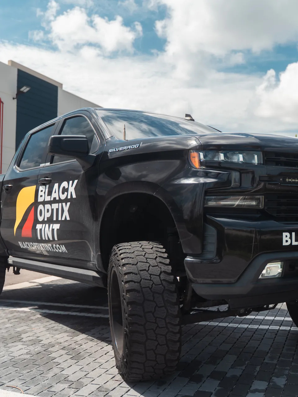 Black Optix Tint wrapped Silverado parked outside the shop