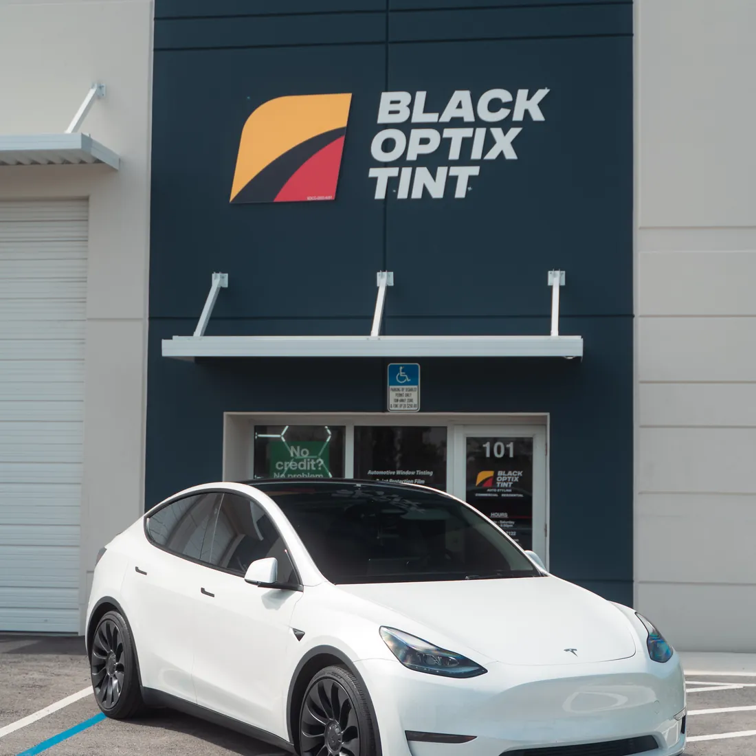 White Tesla Model Y parked outside the Black Optix Tint Doral shop