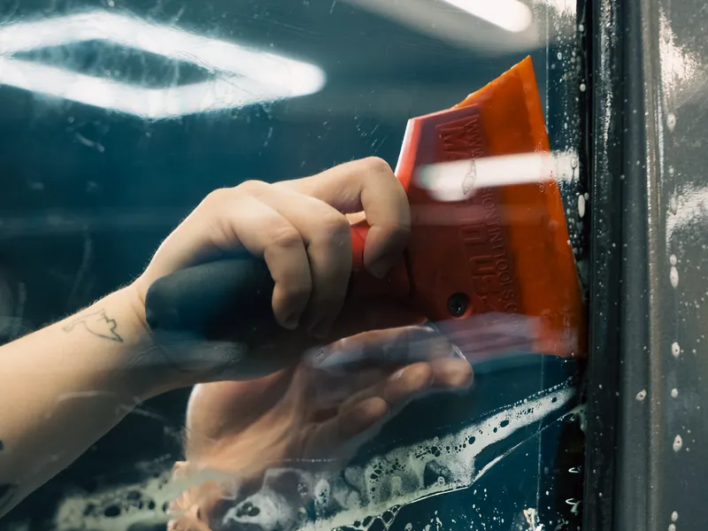Squeegeeing freshly installed window film on a door glass
