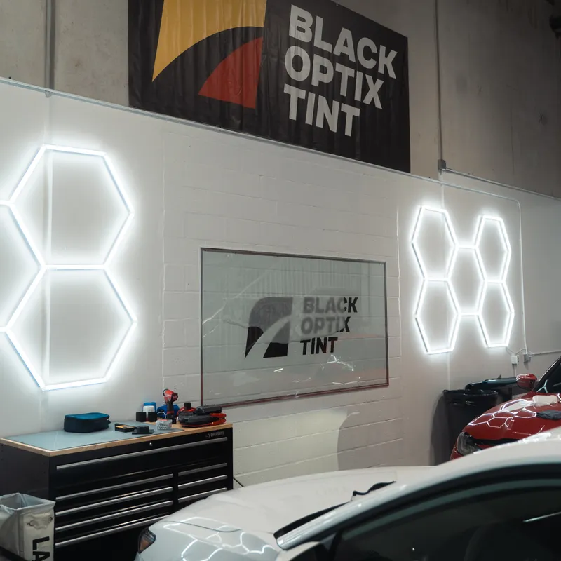 Black Optix Tint install bay with hexagon lighting and cars in progress