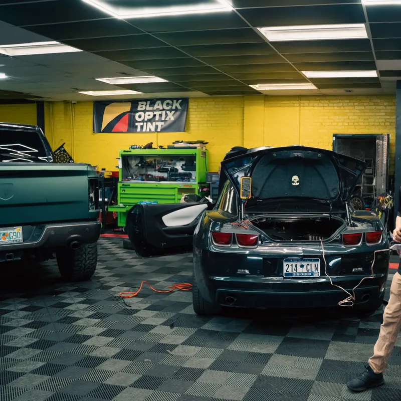 Technicians working on a Camaro in a Black Optix Tint bay