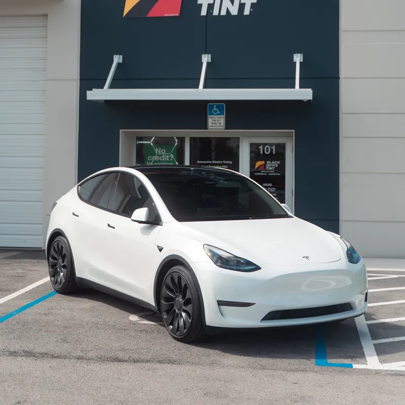White Tesla Model Y with fresh ceramic tint outside a Black Optix Tint shop